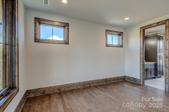 unfurnished room featuring baseboards, visible vents, wood finished floors, and recessed lighting