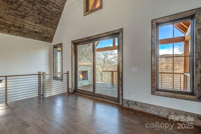 spare room featuring high vaulted ceiling, dark wood-type flooring, plenty of natural light, and visible vents