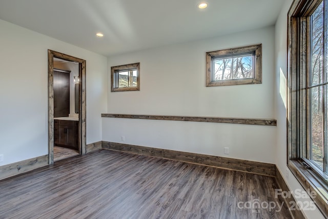 unfurnished room with wood finished floors, a wealth of natural light, and baseboards