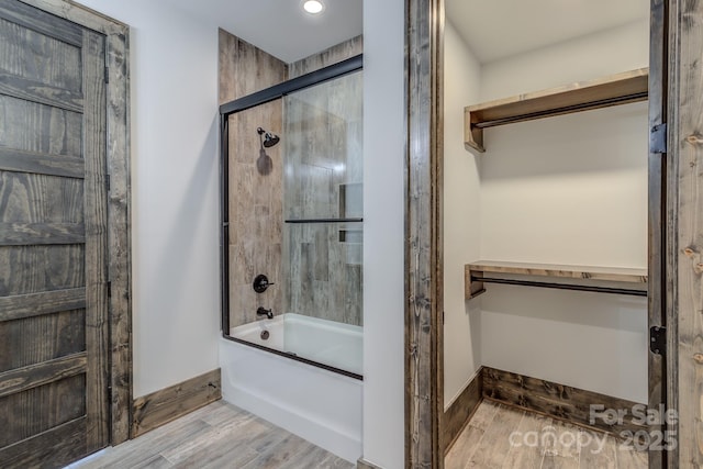 full bathroom with enclosed tub / shower combo, baseboards, and wood finished floors