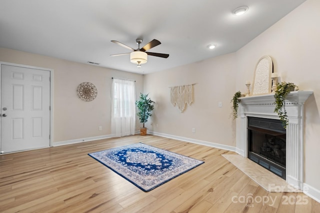 interior space featuring a fireplace with flush hearth, wood finished floors, and baseboards