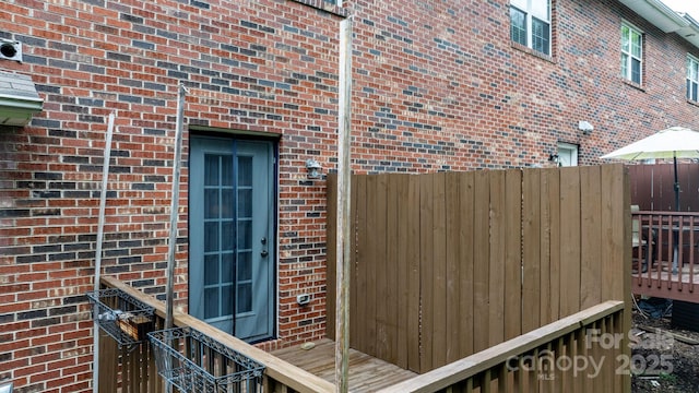 doorway to property with brick siding and fence