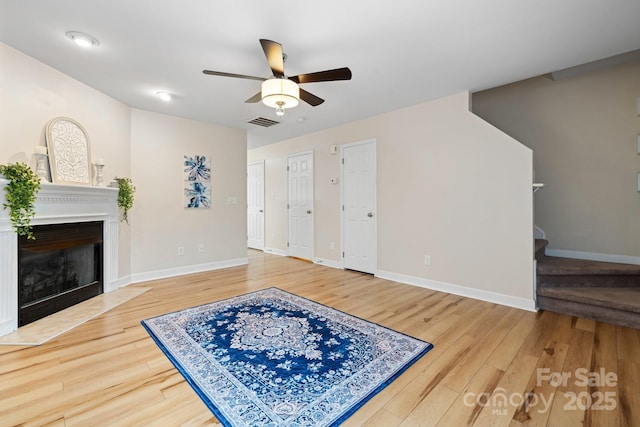 living room with stairway, wood finished floors, visible vents, and baseboards