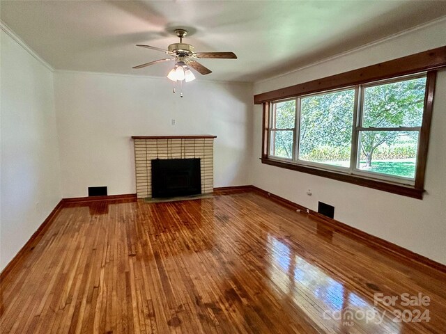 unfurnished living room with ceiling fan, crown molding, hardwood / wood-style flooring, and a brick fireplace