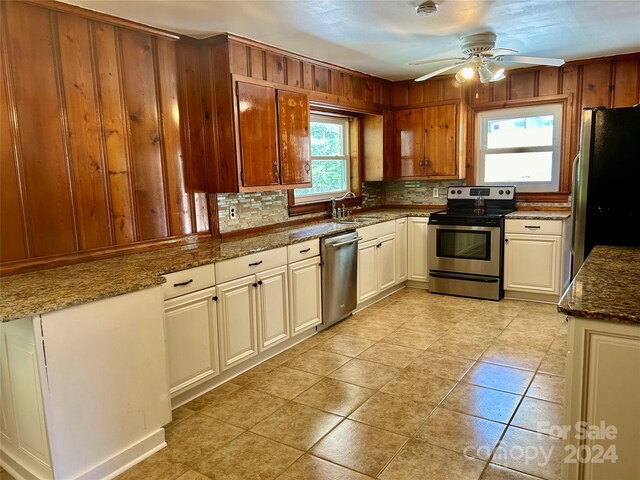 kitchen featuring dark stone counters, light tile patterned floors, sink, appliances with stainless steel finishes, and ceiling fan