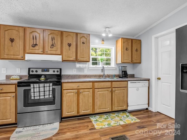 kitchen with ornamental molding, wood-type flooring, appliances with stainless steel finishes, sink, and a textured ceiling