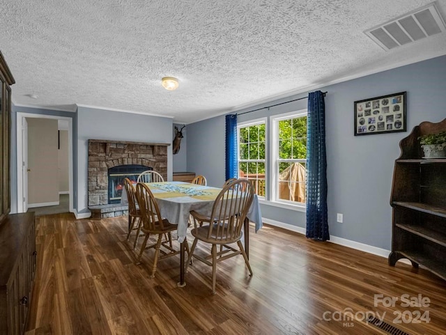 dining area with a stone fireplace, wood-type flooring, and a textured ceiling