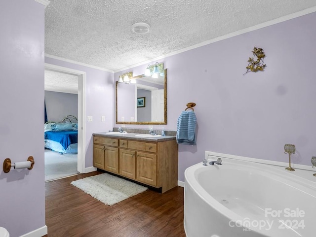 bathroom with hardwood / wood-style flooring, a textured ceiling, dual vanity, and a tub to relax in