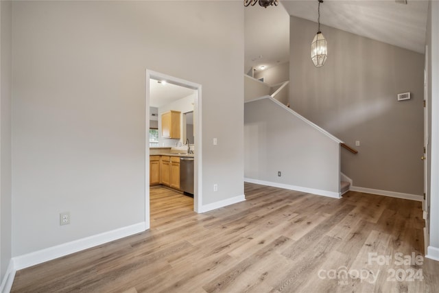 unfurnished living room featuring light wood-style flooring, baseboards, and stairs