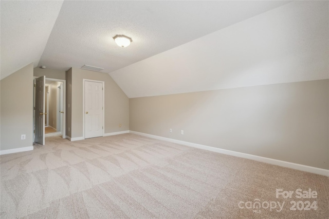 bonus room featuring lofted ceiling, light carpet, a textured ceiling, and baseboards