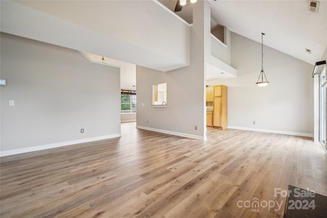 unfurnished living room with baseboards, high vaulted ceiling, visible vents, and light wood-style floors