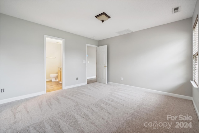 unfurnished bedroom featuring ensuite bath, baseboards, visible vents, and carpet flooring