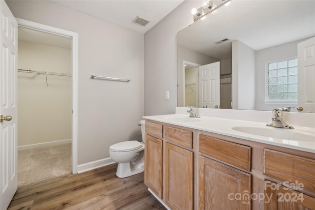 full bathroom with toilet, double vanity, visible vents, and a sink