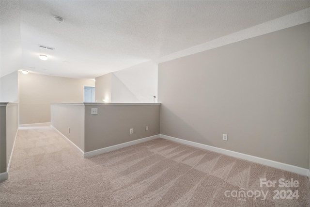 carpeted empty room featuring a textured ceiling, visible vents, and baseboards