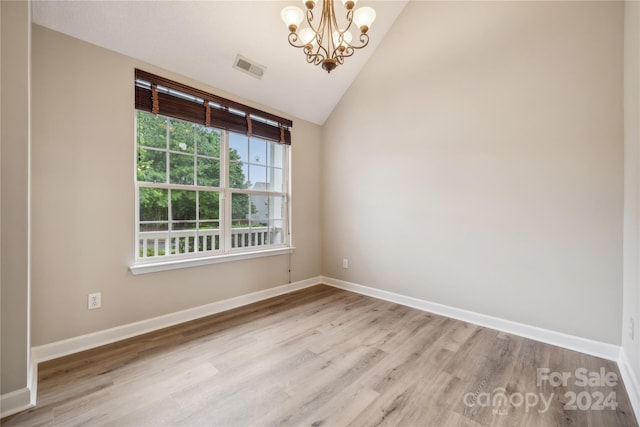 empty room featuring visible vents, a notable chandelier, baseboards, and wood finished floors