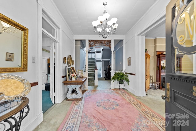 entryway with crown molding, light carpet, and a chandelier