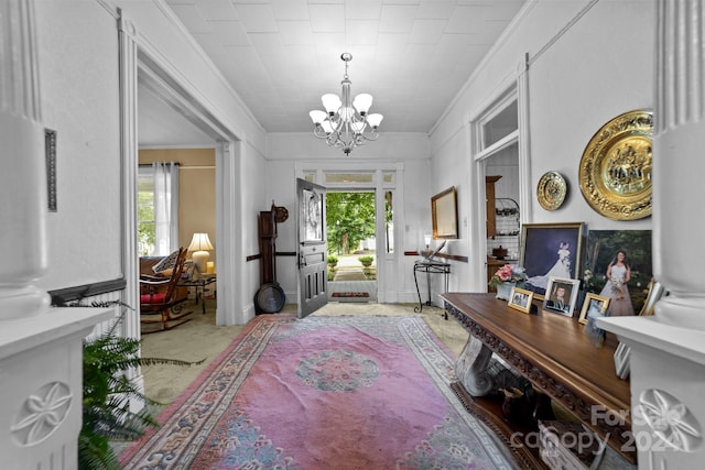 foyer entrance featuring crown molding, a notable chandelier, carpet flooring, and a wealth of natural light