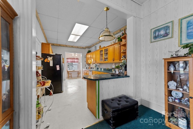 kitchen featuring a drop ceiling, hanging light fixtures, stainless steel fridge, and kitchen peninsula