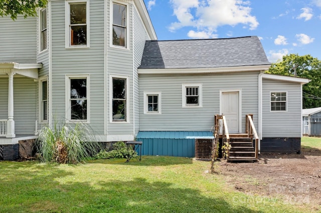 rear view of property featuring a yard and central AC unit