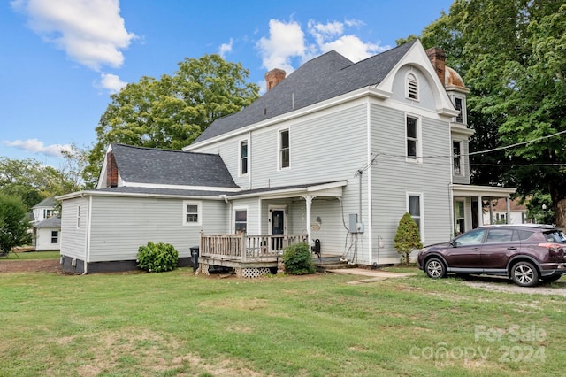 rear view of property featuring a yard and a deck