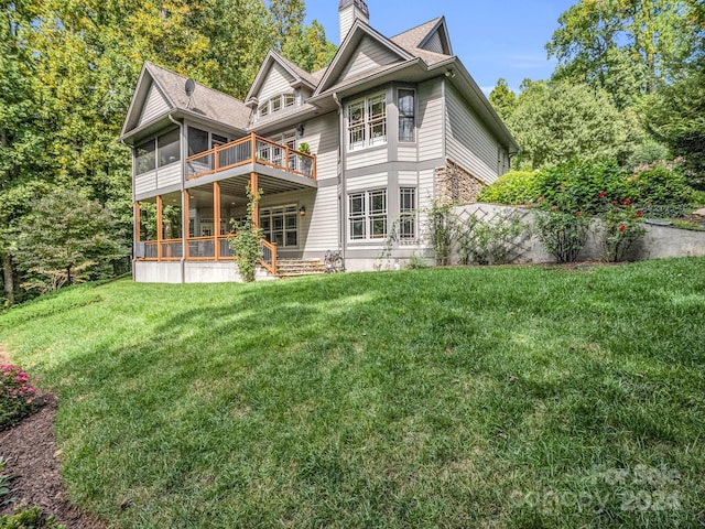 rear view of property featuring a lawn and a sunroom