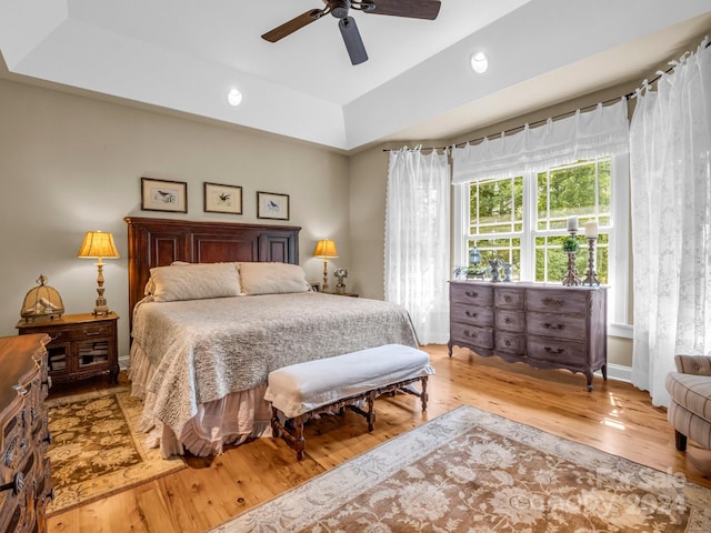 bedroom featuring a raised ceiling, ceiling fan, and light hardwood / wood-style floors