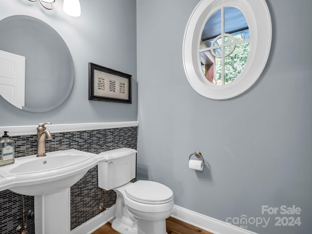 bathroom with hardwood / wood-style floors, backsplash, and toilet