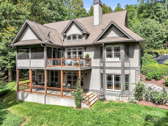 rear view of house with a yard, a wooden deck, and a sunroom