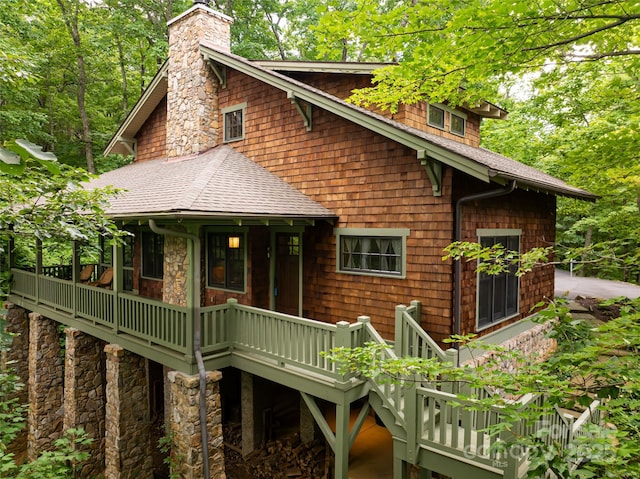 rustic home featuring stone siding, roof with shingles, and a chimney