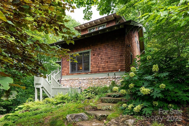 view of home's exterior with stone siding and stairway