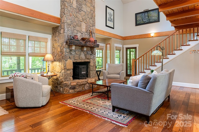 living area with a wealth of natural light, stairway, baseboards, and wood-type flooring