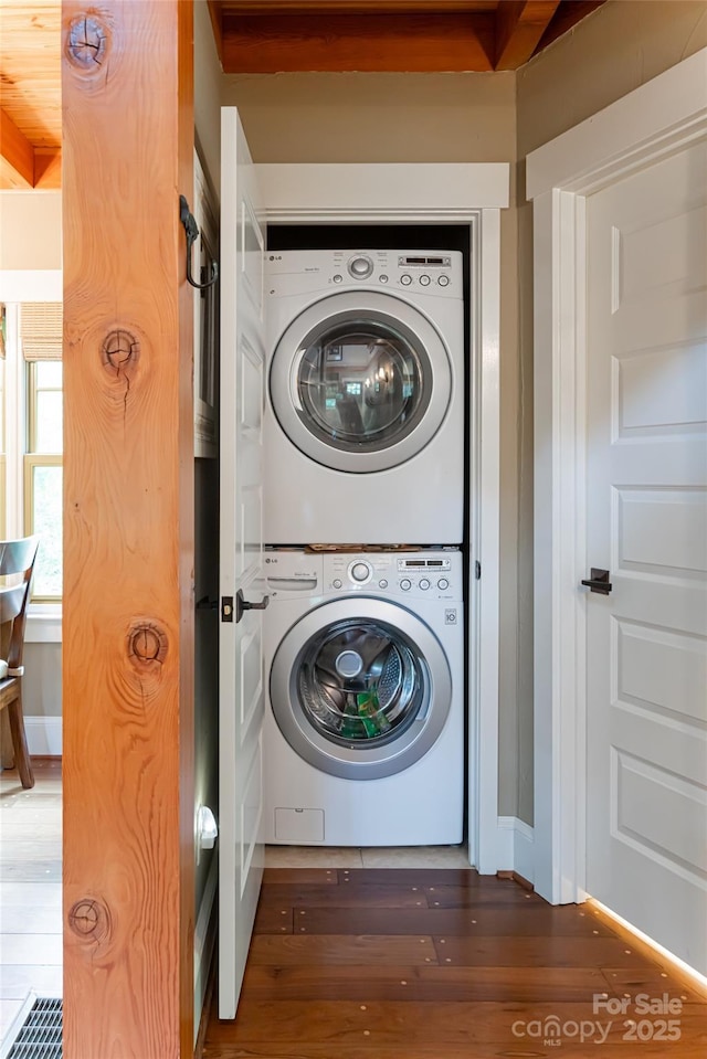 laundry area with laundry area, stacked washer and clothes dryer, and wood finished floors