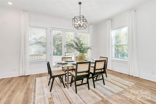 dining space with light wood-type flooring, an inviting chandelier, and crown molding