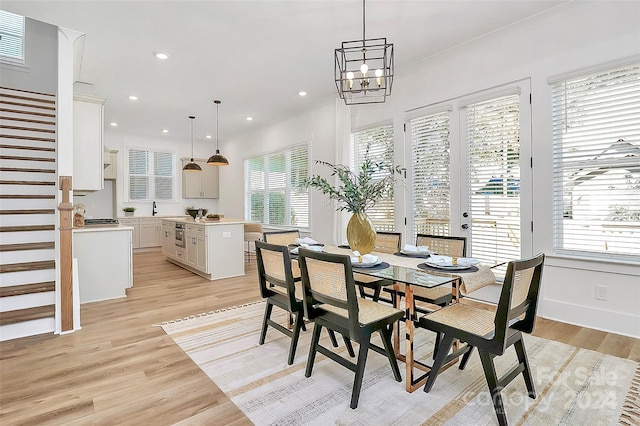 dining area featuring light hardwood / wood-style floors, sink, a notable chandelier, and a healthy amount of sunlight