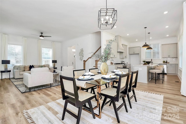 dining area with ceiling fan with notable chandelier and light hardwood / wood-style flooring