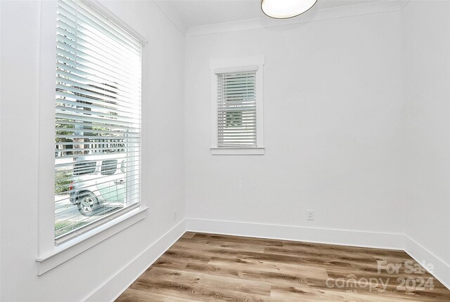 spare room with hardwood / wood-style floors, ornamental molding, and plenty of natural light