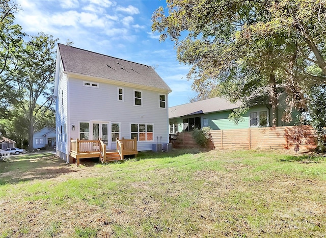 rear view of house with a lawn and a wooden deck