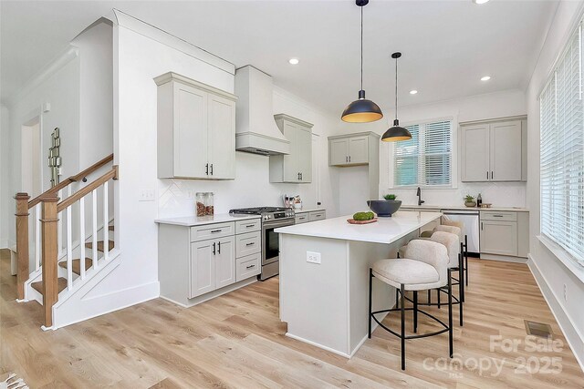 3230 Rogers St, Charlotte, NC 28208 - kitchen with a kitchen breakfast bar, light wood-type flooring, a kitchen island, appliances with stainless steel finishes, and custom exhaust hood