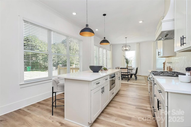 3230 Rogers St, Charlotte, NC 28208 - kitchen with light countertops, premium range hood, a breakfast bar, stainless steel gas range, and light wood-style flooring