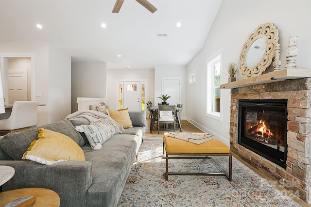 living room featuring a fireplace, ceiling fan, and light wood-type flooring