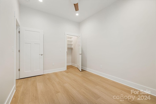 unfurnished bedroom featuring light hardwood / wood-style flooring, ceiling fan, a spacious closet, and a closet