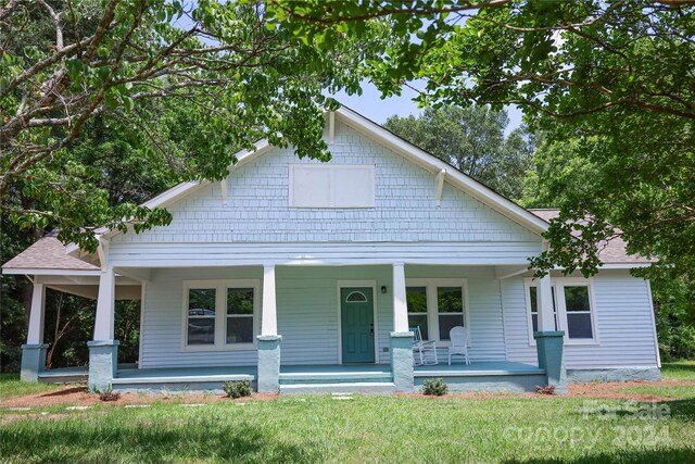 view of front of home featuring covered porch and a front lawn