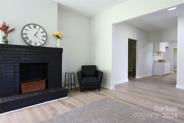 living area featuring a brick fireplace and light hardwood / wood-style flooring