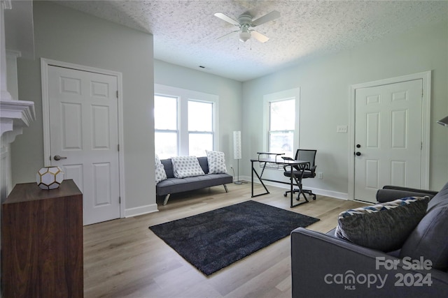 living room featuring ceiling fan, a textured ceiling, and light hardwood / wood-style floors