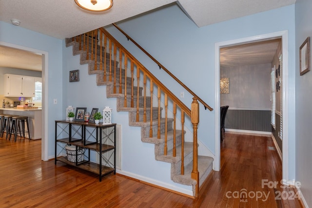 staircase featuring hardwood / wood-style flooring and a textured ceiling