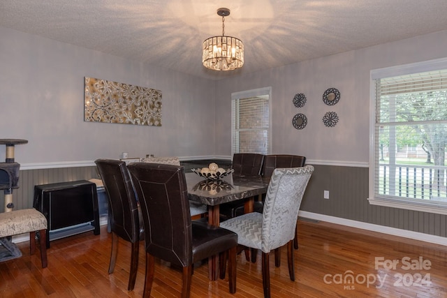 dining area with hardwood / wood-style flooring, an inviting chandelier, a textured ceiling, and a wealth of natural light