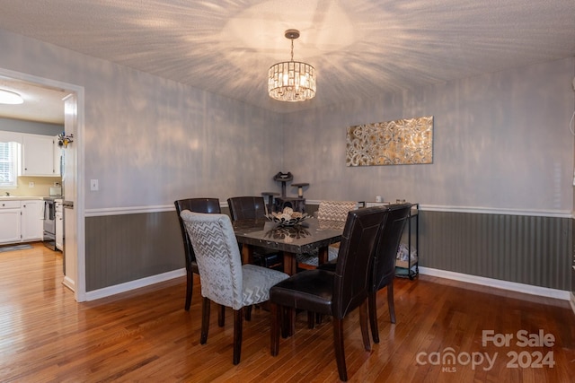 dining area featuring an inviting chandelier, hardwood / wood-style flooring, and a textured ceiling