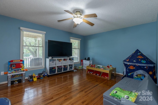 playroom featuring wood-type flooring, ceiling fan, and a textured ceiling