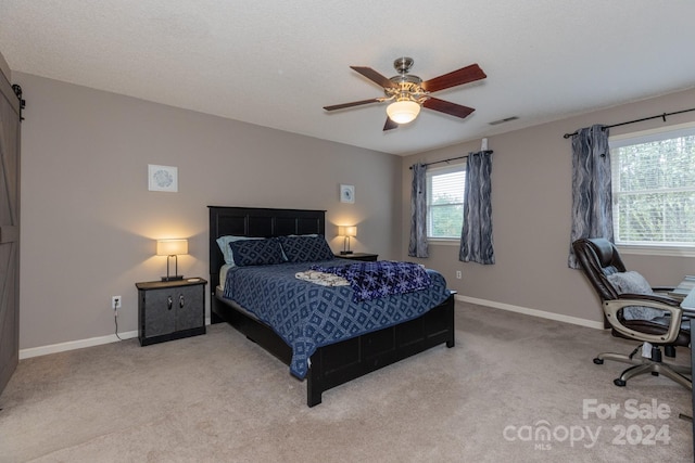 bedroom with a barn door, carpet floors, a textured ceiling, and ceiling fan