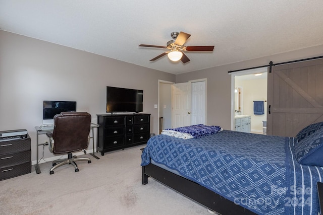 carpeted bedroom featuring connected bathroom, a barn door, and ceiling fan